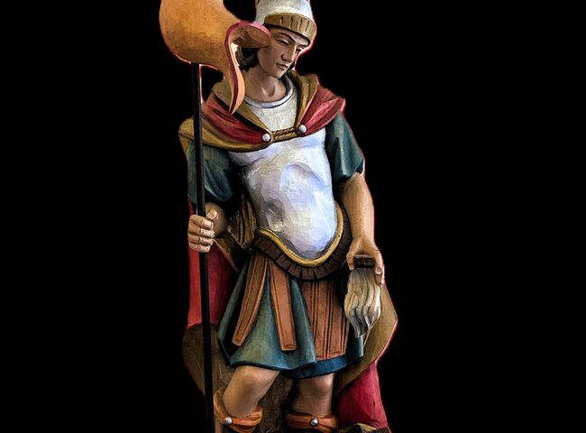 Eine detailreiche Statue eines römischen Kriegers mit Fahne und Rüstung steht majestätisch im Vordergrund.